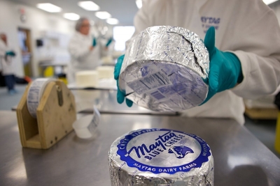 Photo of retailer handling wheels of Maytag cheese